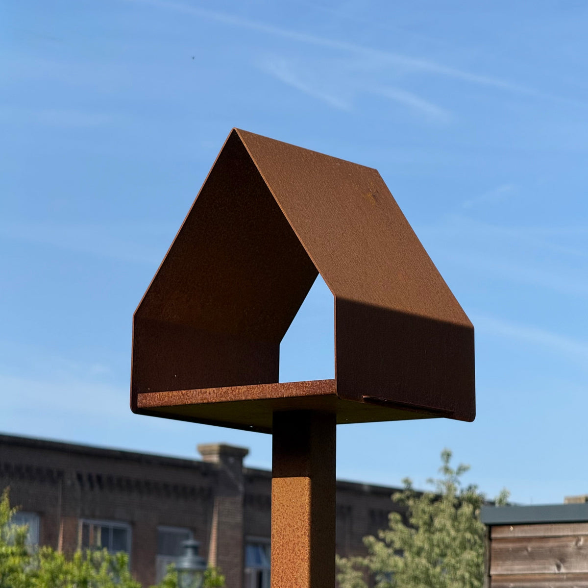 Sfeerfoto van Vogelvoederhuis KOV van cortenstaal op een paal in de tuin